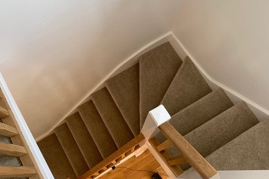 Staircase - mid-sized contemporary carpeted curved wood railing staircase idea in Manchester with carpeted risers