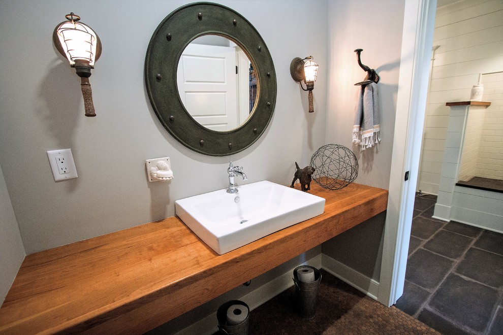 Small farmhouse shower room bathroom in New York with open cabinets, light wood cabinets, an alcove bath, a shower/bath combination, a two-piece toilet, yellow tiles, porcelain tiles, grey walls, cork flooring, a vessel sink and wooden worktops.