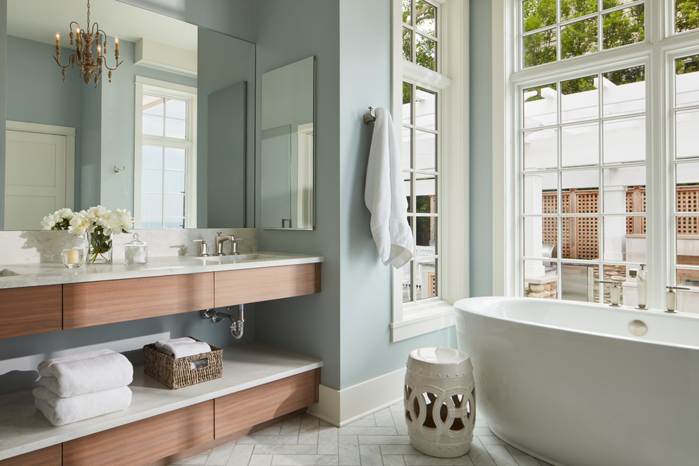 Freestanding bathtub - mid-sized coastal master marble floor and white floor freestanding bathtub idea in Chicago with flat-panel cabinets, medium tone wood cabinets, blue walls, an undermount sink and marble countertops
