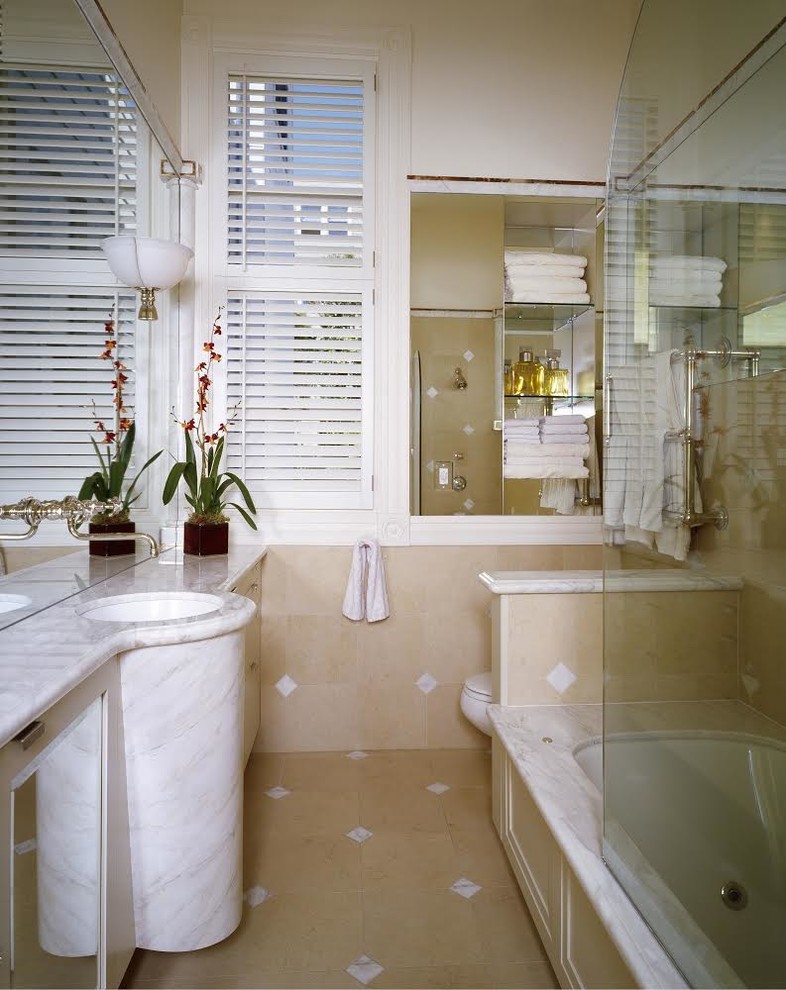 Example of a classic bathroom design in Other with marble countertops and an undermount tub