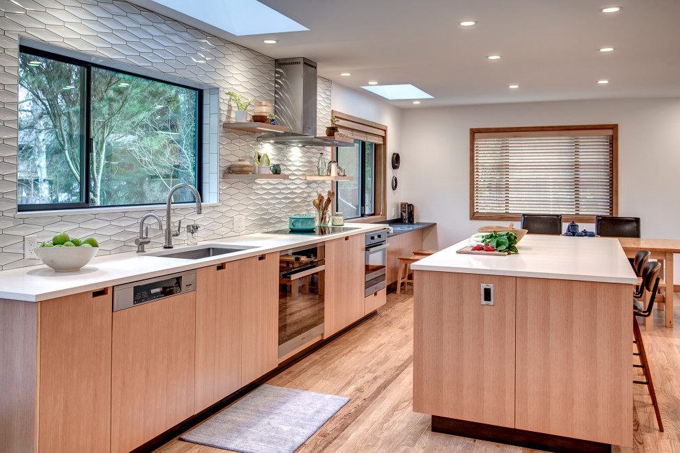 Example of a large minimalist light wood floor kitchen design in Seattle with an undermount sink, flat-panel cabinets, light wood cabinets, quartz countertops, white backsplash, porcelain backsplash, stainless steel appliances, an island and white countertops