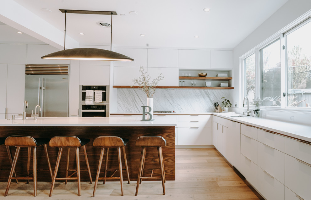 Inspiration for a contemporary l-shaped medium tone wood floor and brown floor kitchen remodel in Seattle with an undermount sink, flat-panel cabinets, white cabinets, white backsplash, stainless steel appliances, an island and white countertops