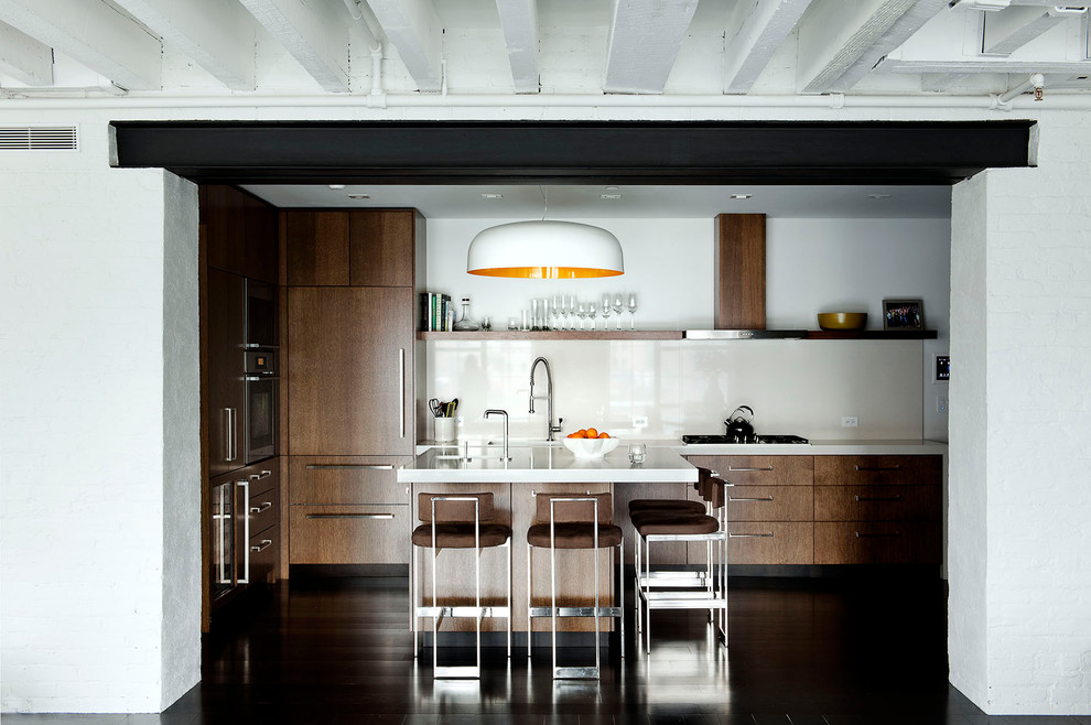 Urban kitchen photo in New York with flat-panel cabinets, dark wood cabinets, white backsplash, paneled appliances and quartz countertops