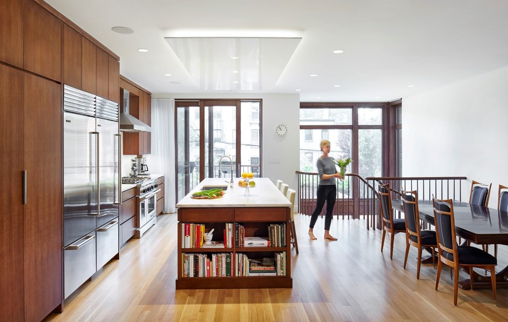 Trendy light wood floor eat-in kitchen photo in New York with an undermount sink, flat-panel cabinets, medium tone wood cabinets, stainless steel appliances and an island