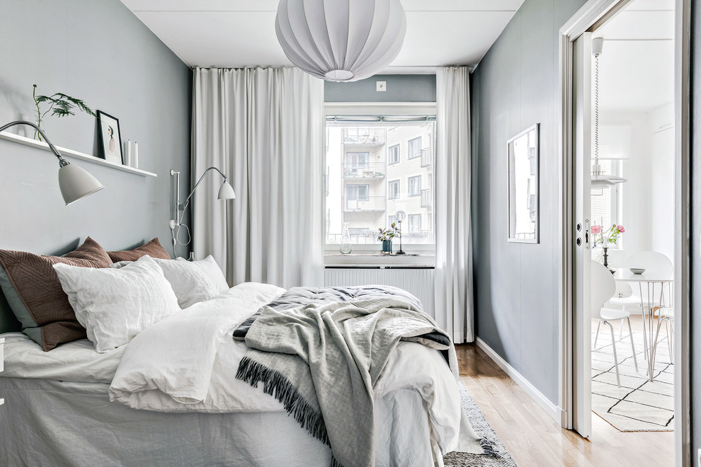 Small scandinavian guest bedroom in Gothenburg with grey walls, light hardwood flooring and beige floors.