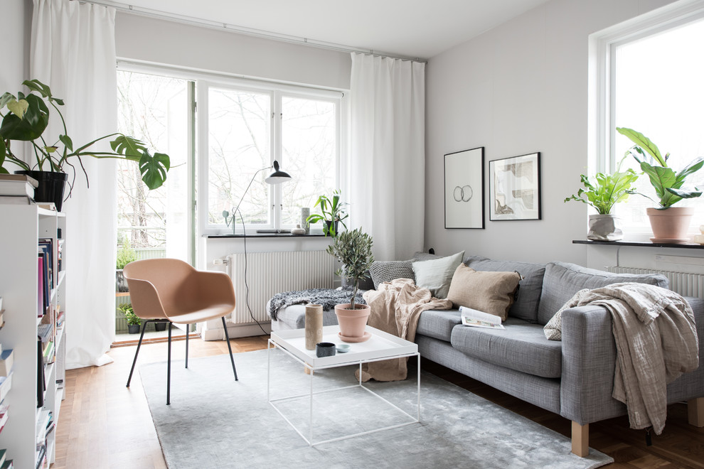 Example of a small danish enclosed medium tone wood floor and beige floor living room design in Gothenburg with white walls and no fireplace