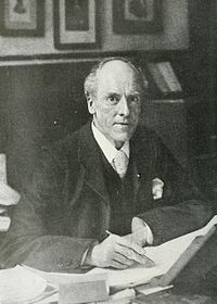 Man seated at his desk looking up at the camera