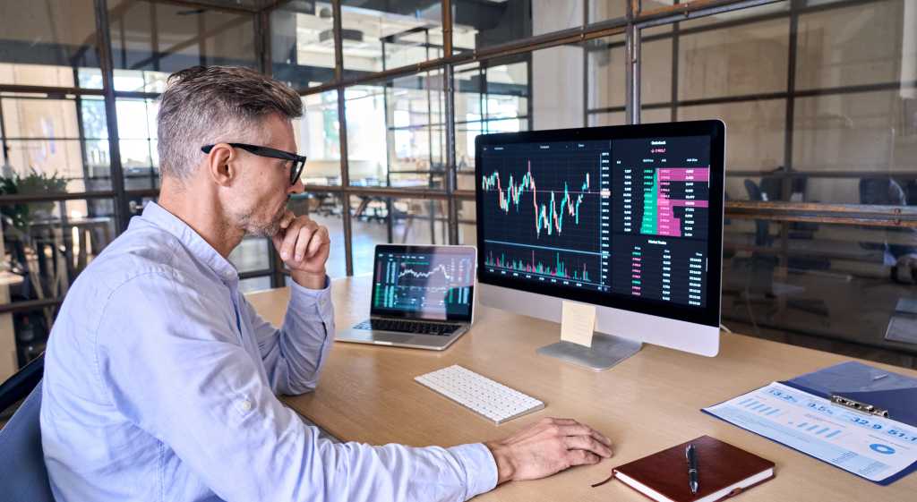 Marketing professional examining data visualizations on laptop and personal computer