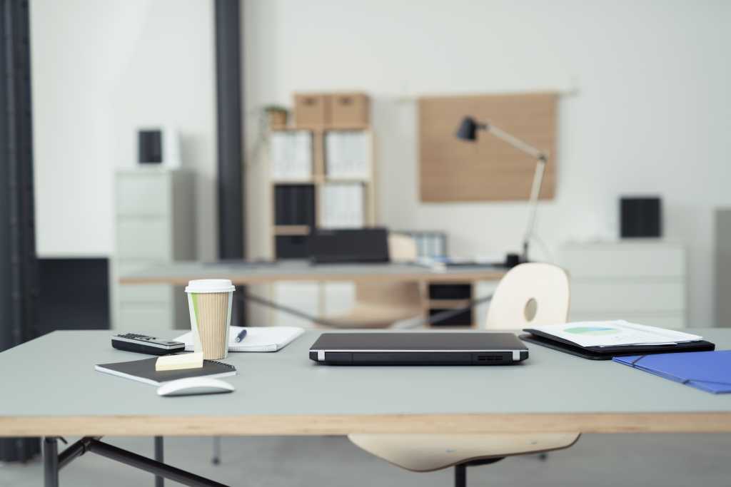 Office Table of a Businessman with Office Supplies, Laptop Computer, Mobile Phone and a Cup of Coffee on Top.