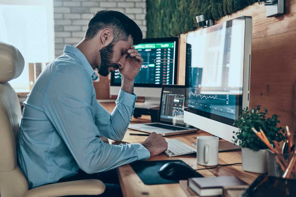 Tired young man in formalwear touching his head while sitting in the office