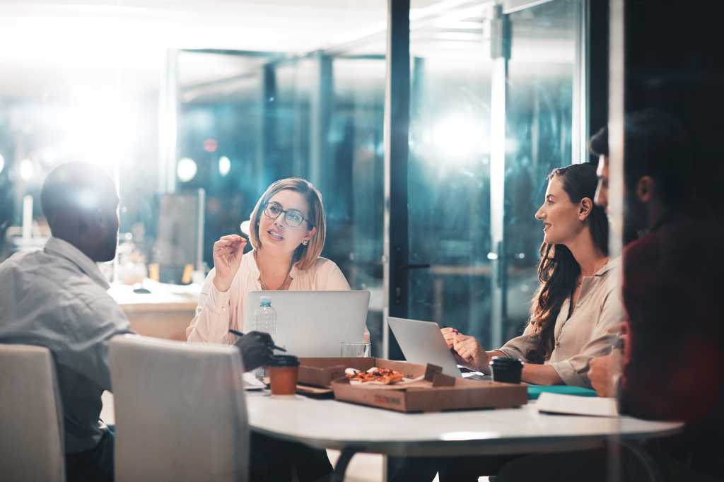 Manager, group and business people planning, discussion or brainstorming on laptop in startup at night. Team, collaboration and project strategy in meeting for creative editor with pizza on deadline