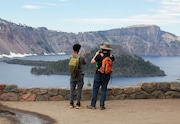 Tourists take pictures at Crater Lake National Park in the early summer, when crowds of visitors begin to return.