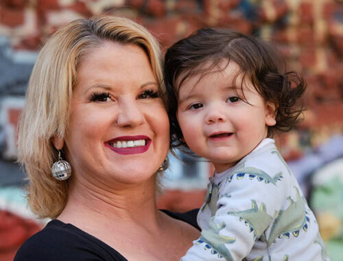 Chelsea, a PROP client, faces the camera smiling and holding her baby