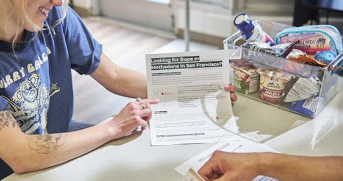 MAT coordinator holds a flier explaining drug treatment options.