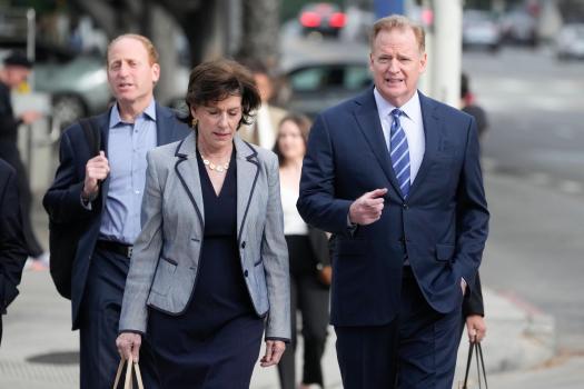 Roger Goodell and others walking down a sidewalk.