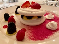 Meringue circles stuffed with berries on a plate with a red powder