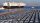 A photo showing rows of cars at a port in China with a large ship, with the label BYD on its side, setting off into the ocean.