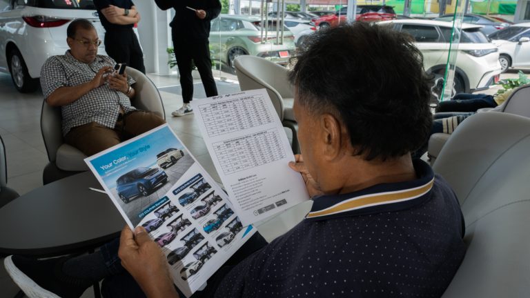 A man browses a BYD car catalogue inside a car showroom.