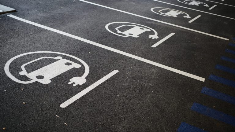 A photograph of car park slots with an electric vehicle pictogram marked on the floor.