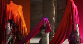 Three statues covered with satin sheets.