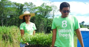 Two 8 Billion Trees team members smiling and carrying over a dozen native species saplings to tree planting site in a remote tree location deep in the Amazon Rainforest(Tocantins Region) on EarthDay during mission to make ecological impact