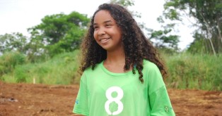 8 Billion Trees Brand Image of young girl smiling with an 8 Billion Trees t-shirt at a tree planting site in the State of Tocantins, a remote area in the Amazon Basin, excited to help plant trees