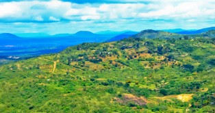 A Kenya planting site from above, with clouds overhead and rolling green hills, and an 8 Billion Trees watermark.