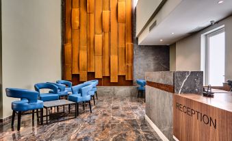 a modern hotel lobby with a reception desk , blue chairs , and wooden panels on the wall at The District Hotel