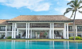 a large , modern building with a thatched roof and multiple balconies , situated next to a pool at The Fortress Resort & Spa