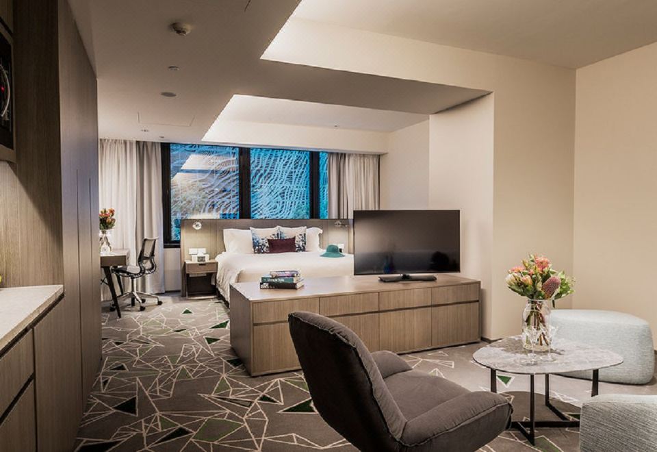 a modern hotel room with a large bed , a television , and a desk , along with other furniture and decorations at Capri by Fraser Brisbane