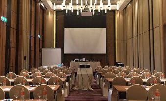 a large conference room with rows of chairs and a projector screen at the front at dusitD2 Khao Yai