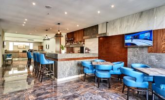 a modern bar with blue chairs and a marble counter , featuring a television on the wall at The District Hotel