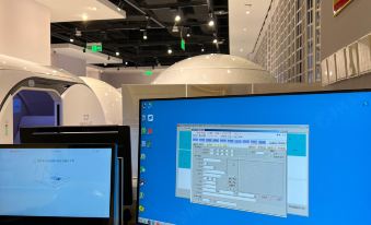 There are three monitors, including a computer monitor, placed on a table in an office, with large screens displaying information at Ke Sleeping Lounge (Beijing Daxing Airport Terminal)