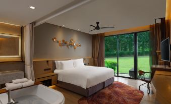 a luxurious hotel room with a large bed , a bathtub , and a view of a golf course at dusitD2 Khao Yai