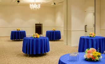 a room with multiple round tables covered in blue tablecloths and chairs arranged around them at Oriental Hotel Tokyo Bay