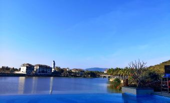 There is a large pool with blue water in front, with the city visible behind it on an overcast day at Holiday Inn & Suites Sanya Yalong Bay