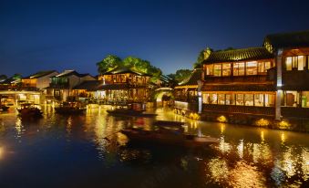 A city at night with boats on the water and buildings lining both sides at WUZHEN Bocheng HOTEL