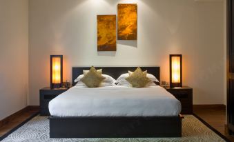 a large bed with a black headboard and white linens is flanked by two lamps on either side at The Fortress Resort & Spa