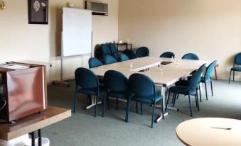 a large , empty conference room with multiple tables and chairs , a whiteboard , and a computer monitor at Plainsman Motel