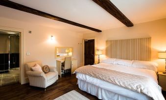 a large bed with white linens is in a room with wooden floors and beams at The Nags Head