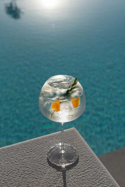 a cocktail with ice and fruit garnish on a table near a pool , possibly indicating a poolside party or celebration at Ikos Dassia Ikos Dassia - All Inclusive Photo