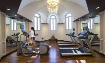 a woman is working out on a treadmill in a gym with treadmills and exercise bikes at Royal Rose Abu Dhabi, a Curio Collection by Hilton Affiliated Hotel