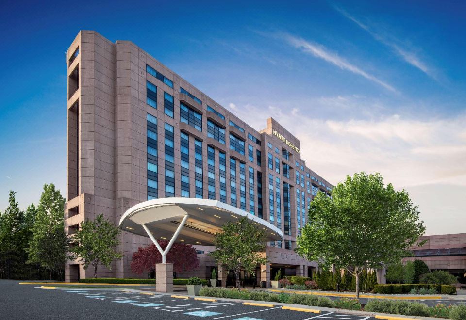 a large hotel with a modern design , surrounded by trees and a parking lot in the foreground at Hyatt Regency Dulles