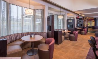 a modern lounge area with wooden floors , pink chairs , and couches , as well as a dining table and bar area at Courtyard Fairfax Fair Oaks