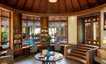 a modern , well - lit room with wooden furniture and large windows offering views of the outdoors at Anantara Dhigu Maldives Resort