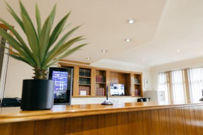 a well - lit hotel lobby with a wooden reception desk and a tv mounted on the wall at Best Western Bradford Guide Post Hotel Best Western Bradford Guide Post Hotel Photo