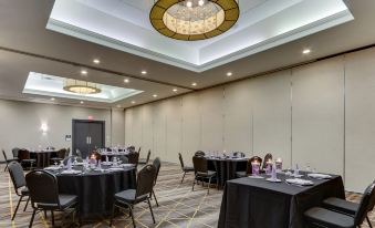 a large conference room with multiple tables and chairs , a chandelier , and a stage at the end at Holiday Inn Staunton Conference Center