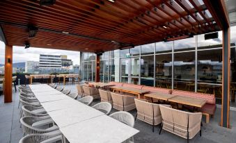 an outdoor dining area with multiple tables and chairs arranged under a wooden pergola , providing shade and seating for guests at Crowne Plaza Hobart, an IHG Hotel