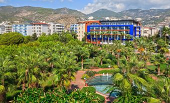 a hotel surrounded by lush greenery , with a large pool and a bridge nearby in the background at Gardenia Hotel