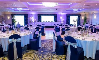 a well - decorated banquet hall with multiple tables covered in white tablecloths and chairs arranged for a formal event at Arklow Bay Hotel